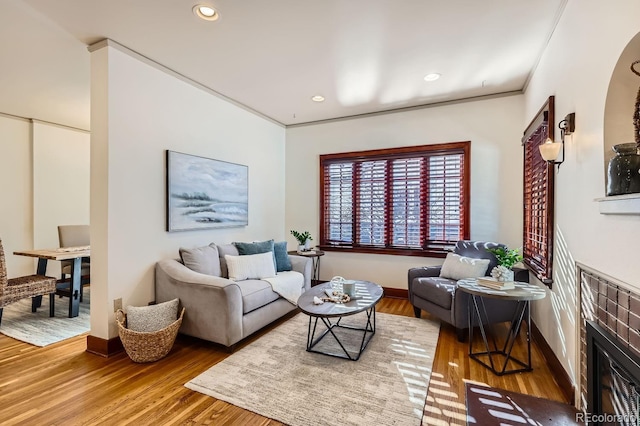 living room featuring hardwood / wood-style flooring, a brick fireplace, and ornamental molding