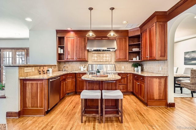 kitchen with range, dishwasher, wall chimney range hood, a kitchen breakfast bar, and kitchen peninsula