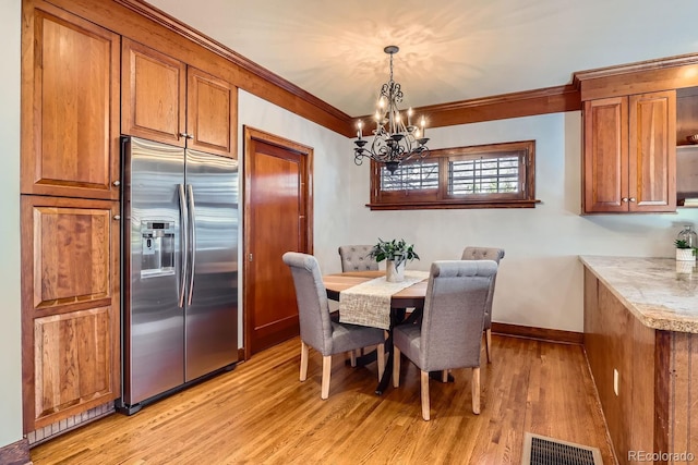 dining area featuring light hardwood / wood-style floors, a notable chandelier, and ornamental molding