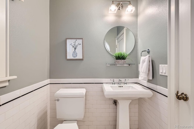 bathroom with toilet and tile walls