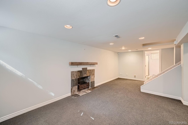 basement with dark colored carpet and a stone fireplace