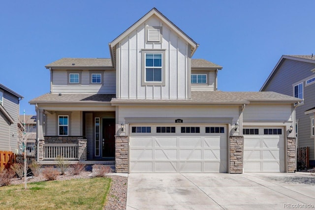 view of front of home with covered porch, driveway, board and batten siding, and stone siding