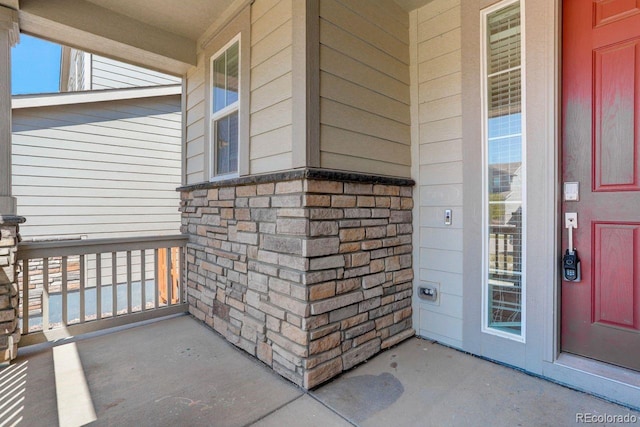 view of exterior entry featuring a porch and stone siding