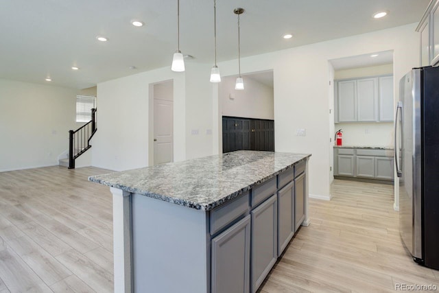 kitchen with freestanding refrigerator, light wood finished floors, a kitchen island, and gray cabinetry