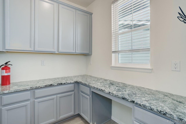 interior space with light stone countertops, gray cabinetry, and a wealth of natural light
