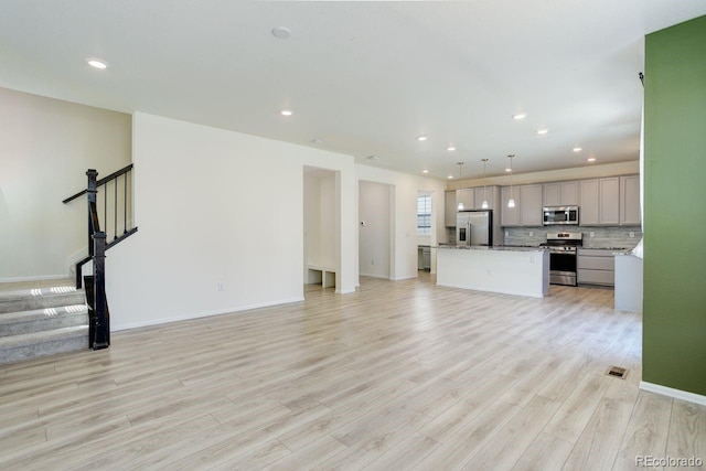 unfurnished living room with stairs, recessed lighting, baseboards, and light wood-style floors