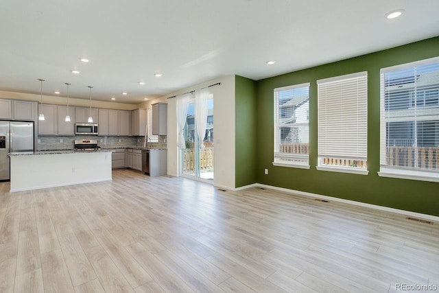 unfurnished living room with visible vents, recessed lighting, light wood finished floors, and a wealth of natural light