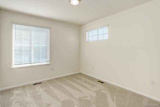 carpeted spare room featuring visible vents and baseboards
