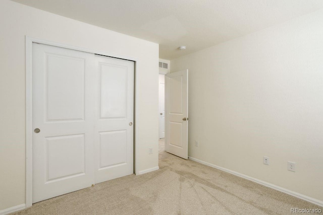 unfurnished bedroom featuring visible vents, baseboards, a closet, and light colored carpet