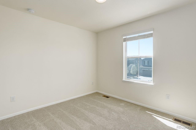 spare room with baseboards, light carpet, and visible vents