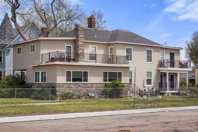 501 N Weber, Colorado Springs, CO 80903 - back of house with stucco siding, a fenced front yard, stone siding, and a balcony