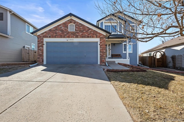 traditional-style house featuring a porch, an attached garage, brick siding, fence, and concrete driveway