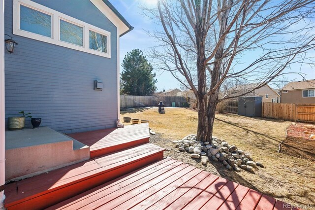 wooden deck with an outbuilding, a yard, and a fenced backyard