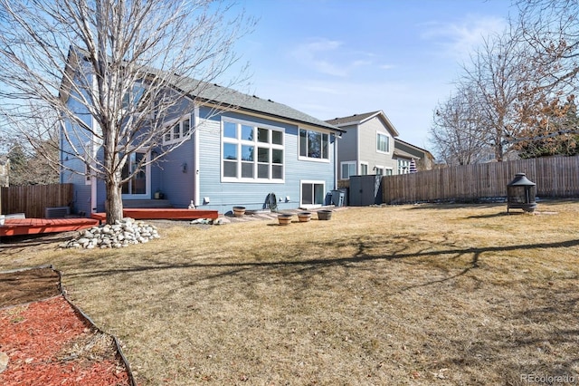 rear view of house featuring a fire pit, a yard, fence, and a wooden deck