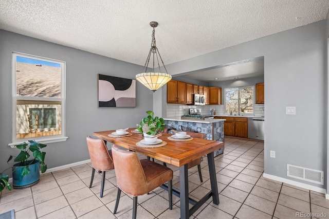 dining area with baseboards, visible vents, a textured ceiling, and light tile patterned flooring