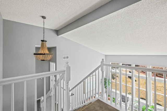 interior space featuring visible vents, a textured ceiling, and an upstairs landing