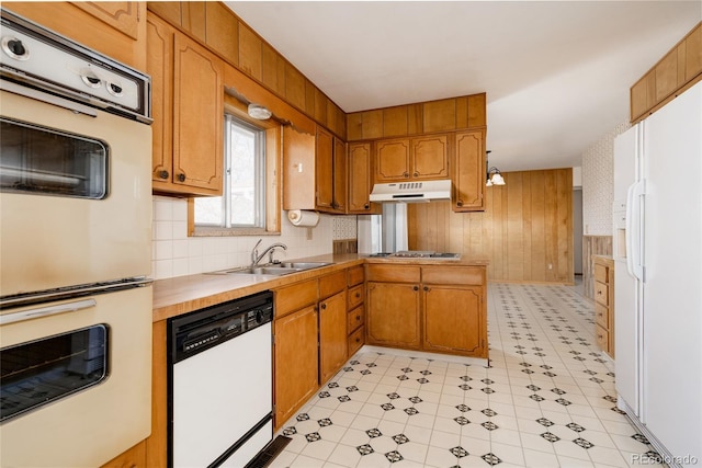 8895 Morton Rd, Niwot, CO 80503 - kitchen featuring white appliances, under cabinet range hood, brown cabinetry, wooden walls, and light countertops