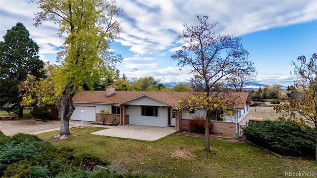 8895 Morton Rd, Niwot, CO 80503 - rear view of house with a lawn, brick siding, an attached garage, driveway, and a chimney