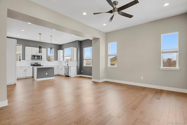 unfurnished living room with sink, ceiling fan, and light hardwood / wood-style floors