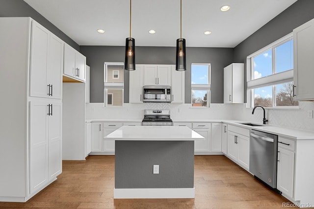 kitchen featuring sink, a kitchen island, white cabinets, and stainless steel appliances