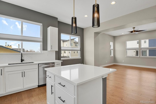 kitchen featuring light wood-type flooring, white cabinetry, a center island, sink, and stainless steel dishwasher