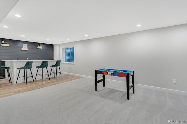 rec room featuring light hardwood / wood-style flooring and bar area