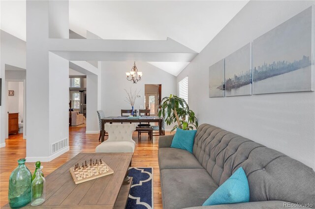 living room featuring wood-type flooring, high vaulted ceiling, and an inviting chandelier