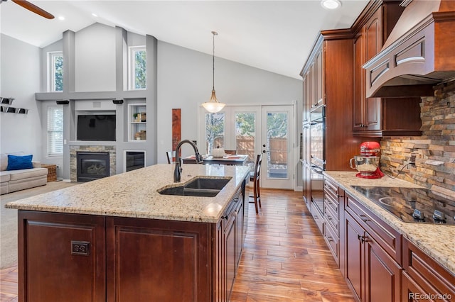 kitchen with black electric cooktop, a wealth of natural light, sink, and light wood-type flooring