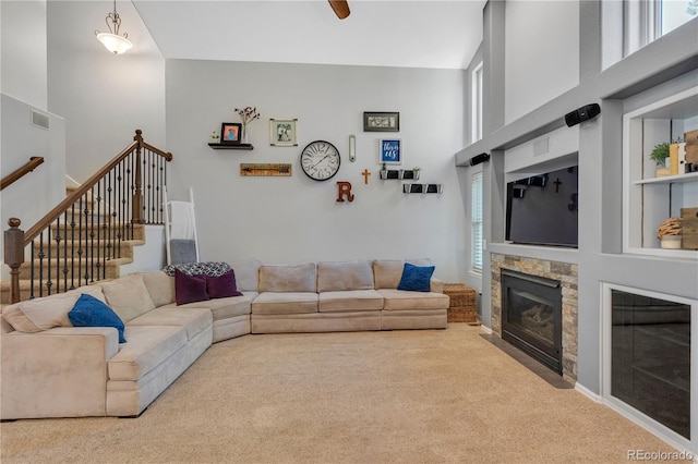 living room featuring a stone fireplace, light colored carpet, and a high ceiling