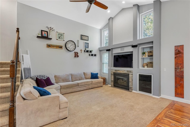 living room with a stone fireplace, ceiling fan, high vaulted ceiling, and hardwood / wood-style flooring