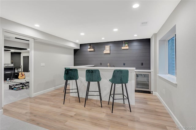 bar featuring wine cooler and light hardwood / wood-style floors