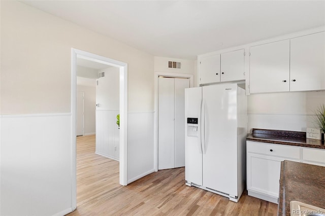 kitchen featuring white cabinetry, white refrigerator with ice dispenser, and light hardwood / wood-style floors