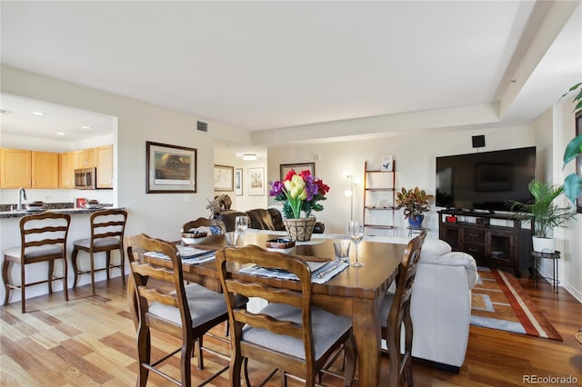 dining space with light hardwood / wood-style flooring and sink