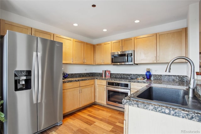 kitchen with light brown cabinets, light wood-type flooring, stainless steel appliances, and sink