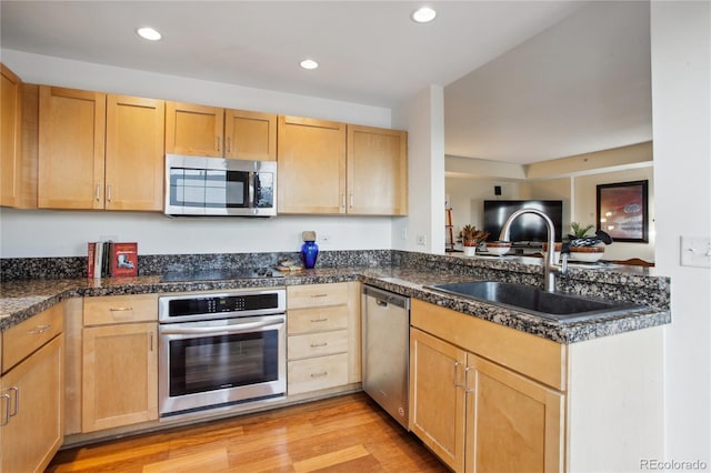 kitchen with light brown cabinets, light wood-type flooring, stainless steel appliances, and sink