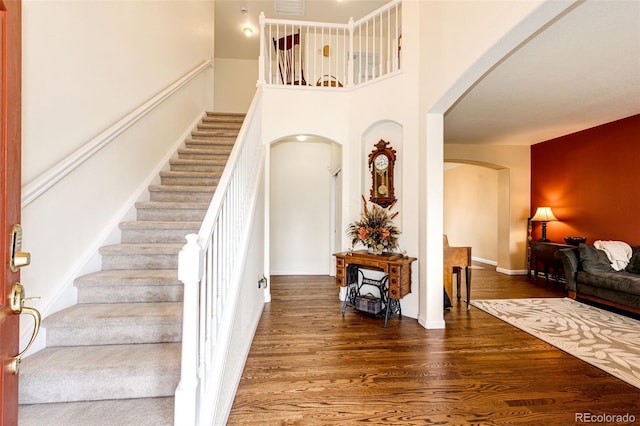 12000 Horseshoe Ln, Parker, CO 80138 - stairs with arched walkways, wood finished floors, a high ceiling, and baseboards