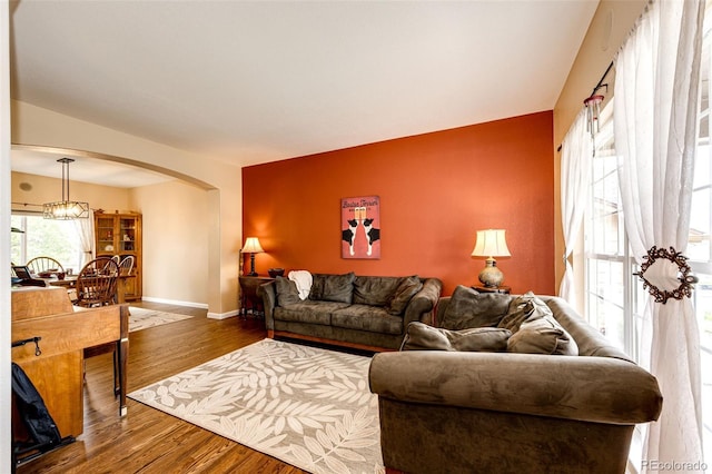 12000 Horseshoe Ln, Parker, CO 80138 - living room featuring arched walkways, wood finished floors, baseboards, and a chandelier