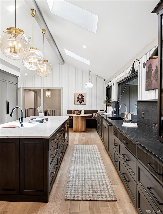 5290 Nassau Cir E, Cherry Hills Village, CO 80113 - kitchen with light stone counters, light wood-style flooring, lofted ceiling with skylight, and a sink