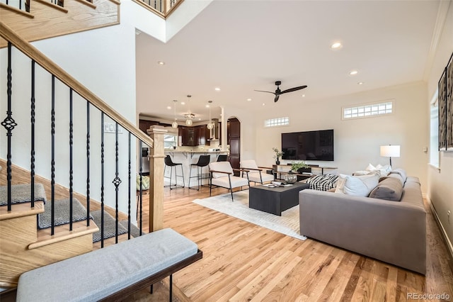 living room featuring crown molding, light hardwood / wood-style floors, and ceiling fan