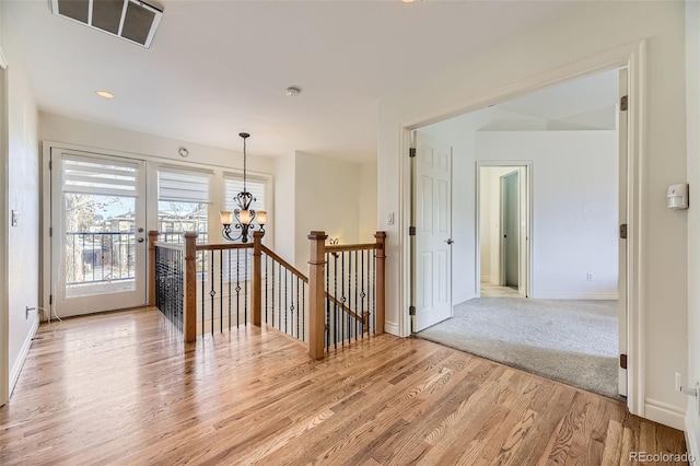 corridor with an inviting chandelier and light hardwood / wood-style flooring