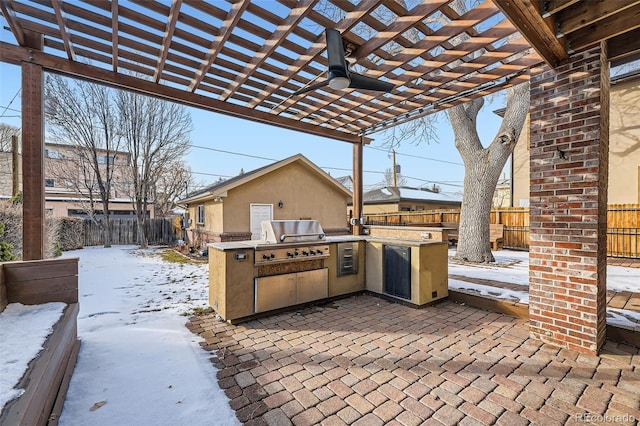 snow covered patio featuring an outdoor kitchen, area for grilling, ceiling fan, and a pergola