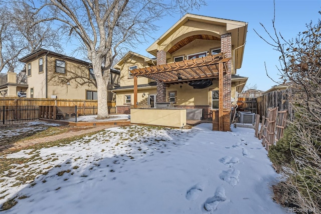 snow covered rear of property with central AC unit and a pergola