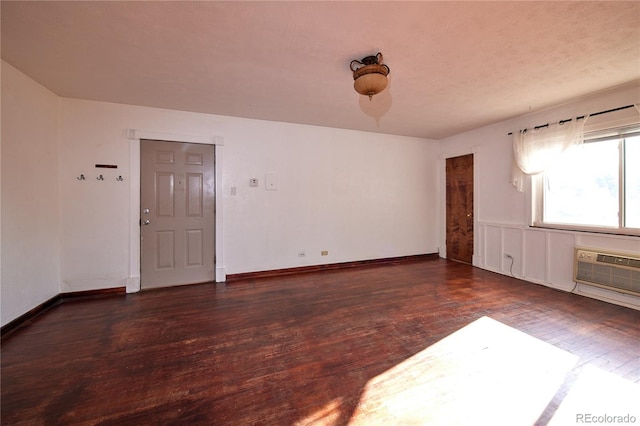 unfurnished room with a wall unit AC and dark wood-type flooring