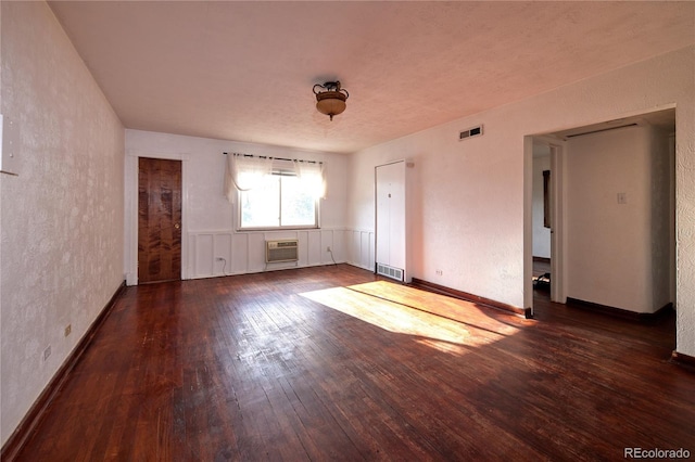 spare room featuring an AC wall unit and dark wood-type flooring