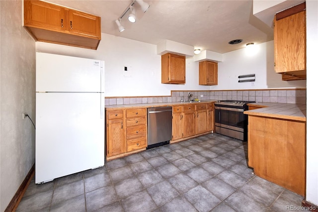 kitchen featuring tile countertops, decorative backsplash, sink, and appliances with stainless steel finishes