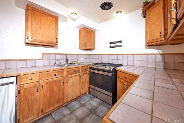 kitchen featuring tasteful backsplash, sink, tile counters, and appliances with stainless steel finishes