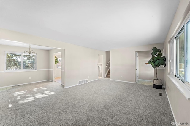 empty room featuring light carpet and a notable chandelier