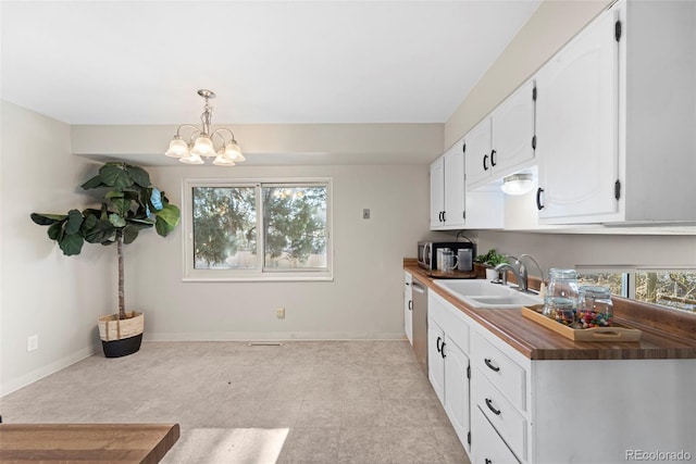 kitchen with hanging light fixtures, butcher block counters, sink, and white cabinetry