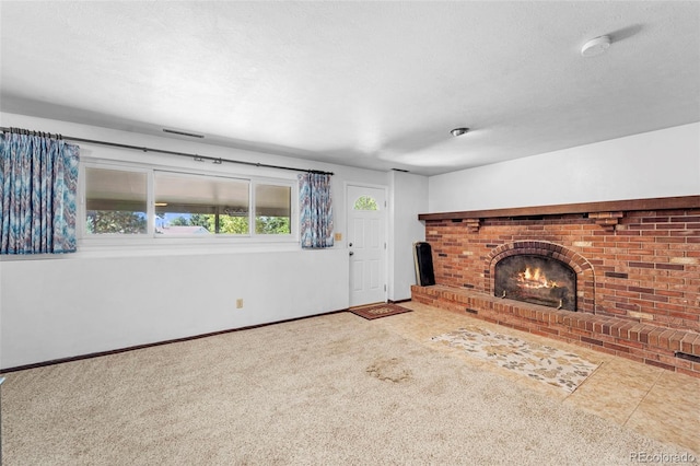 unfurnished living room with carpet, a brick fireplace, and a textured ceiling