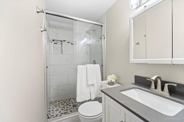 bathroom with a shower with shower door, toilet, and vanity